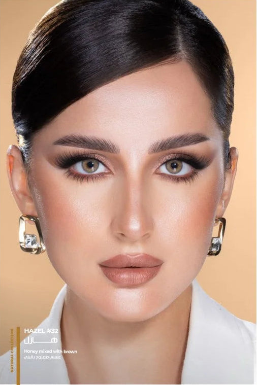 Close-up of a person with makeup and earrings against a beige background